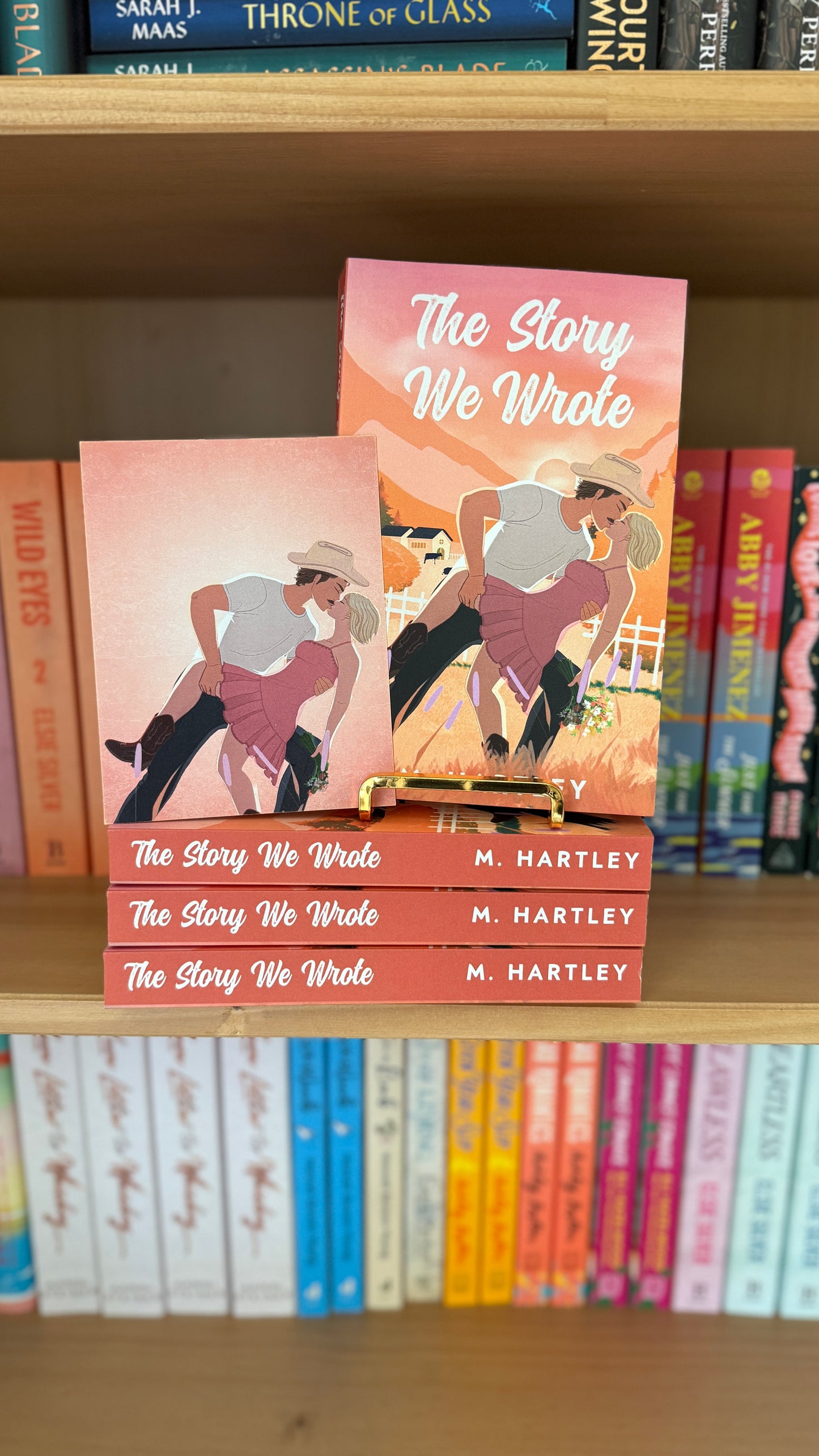 Book titled 'The Story We Wrote' by M. Hartley on a bookshelf with other books.