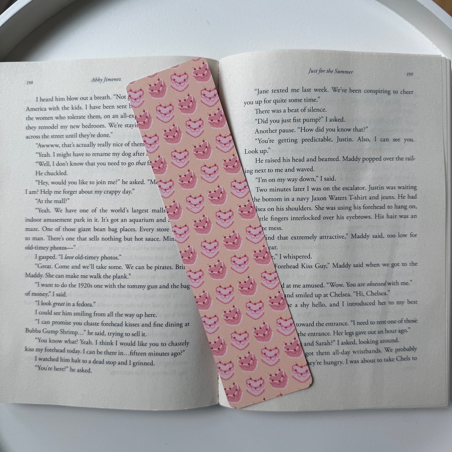 Open book with a pink decorative bookmark on a white surface