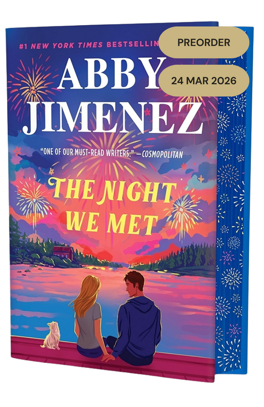 Book cover of 'The Night We Met' by Abby Jimenez with a couple and dog watching fireworks over a lake.