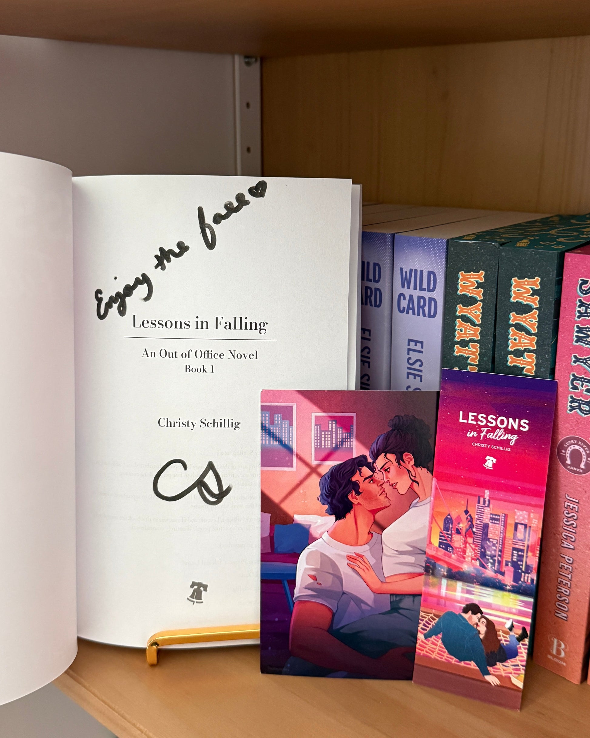 Books on a shelf with 'Lessons in Falling' series prominently displayed