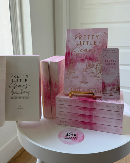 Stack of books titled 'Pretty Little Liars' on a white stool with a white wall background