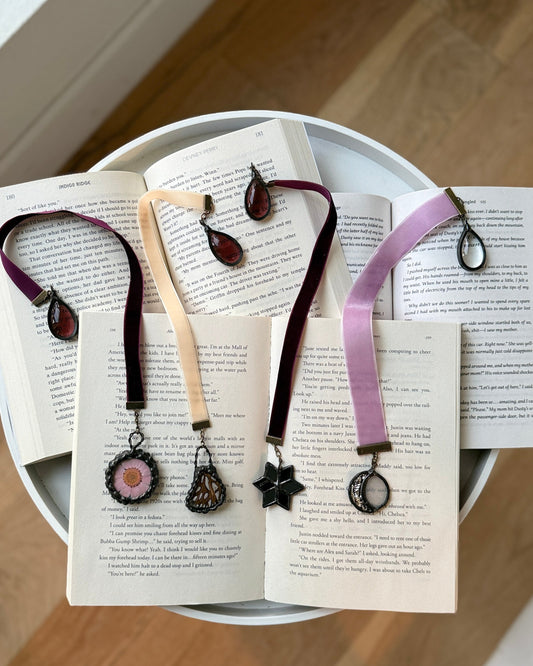 Jewelry with star and circular designs on a white plate over open books.