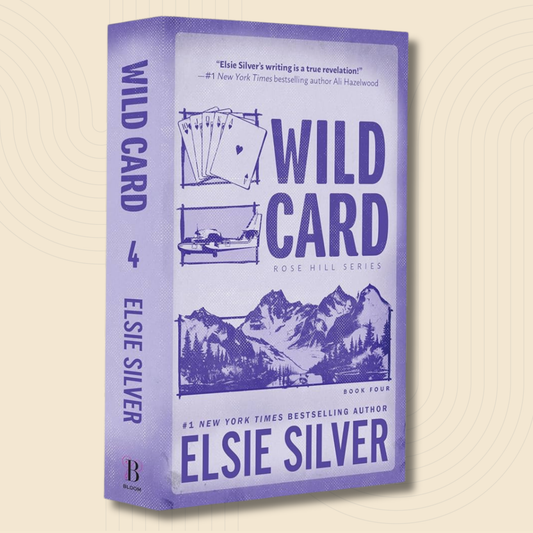 The book 'Wild Card' by Elsie Silver, shown as a 3D box mockup on a light beige background with a subtle circular pattern. The cover and spine are lavender purple with dark purple text and illustrations of playing cards and a mountain landscape.