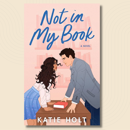 Book cover for the novel 'Not in My Book' by Katie Holt, featuring an illustration of a man and woman leaning over a table with a book between them, set against a light pink background with bookshelves and the title in blue script.