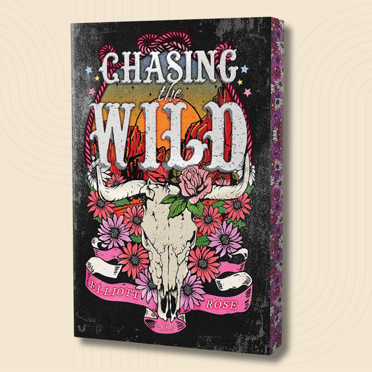 A rectangular wall art canvas or print shown at an angle, featuring the phrase “Chasing the Wild” above a stylized skull surrounded by pink and red flowers on a distressed black background. The side edge shows a floral patterned surface.