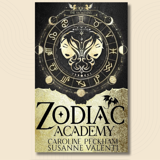 A book cover for 'Zodiac Academy' by Caroline Peckham and Susanne Valenti, featuring a black and gold design with a zodiac wheel, twin faces, and a bat silhouette.