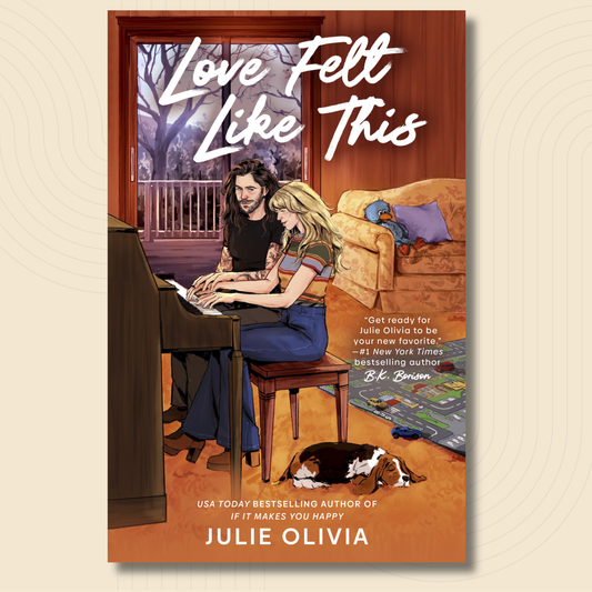 Book cover for 'Love Felt Like This' by Julie Olivia, featuring an illustrated couple sitting together in a warmly lit living room with a piano, couch, and dog.