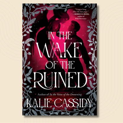 Book cover for 'In the Wake of the Ruined' by Kalie Cassidy, featuring a dark romantic design with silhouetted figures, a vivid magenta-pink glow, and white title text, shown against a light beige background.